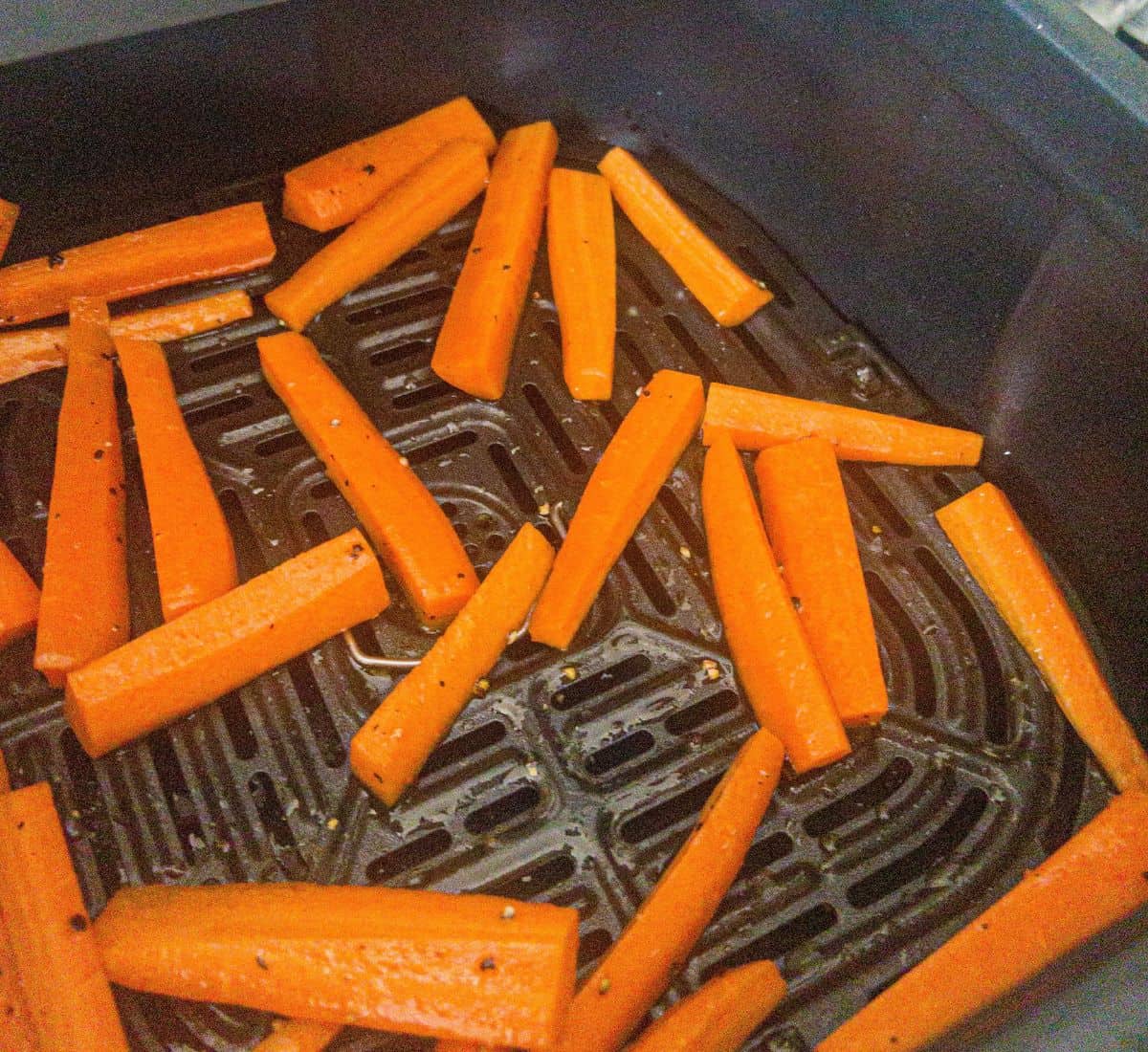 Carrot sticks in an air fryer basket.
