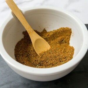 Chermoula spice in a white bowl with a wooden spoon.