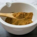 Chermoula spice in a white bowl with a wooden spoon.