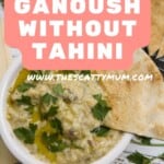 a bowl of baba ganoush garnished with parsley. Triangles of pitta bread in the background.