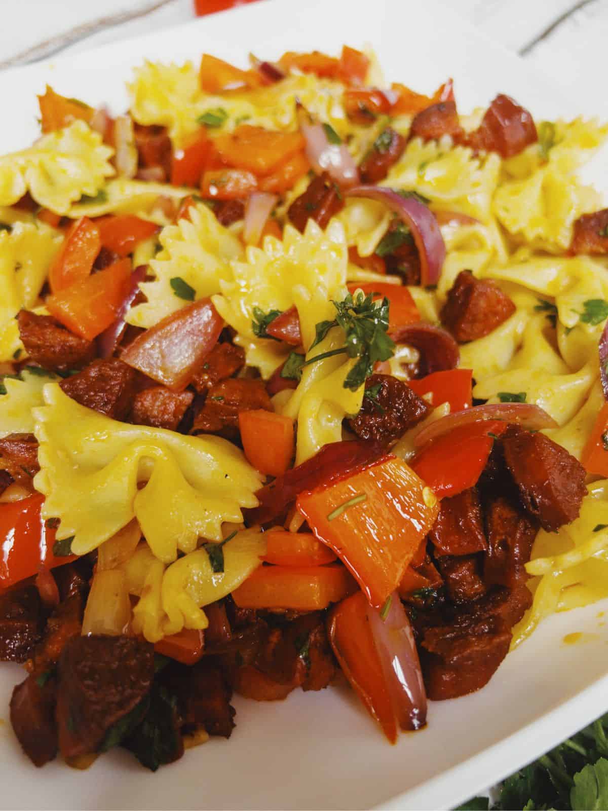 A bowl of bow pasta with chorizo & red peppers.
