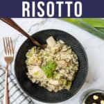A bowl of chicken risotto with a spoon in the bowl and a fork sitting to the side.