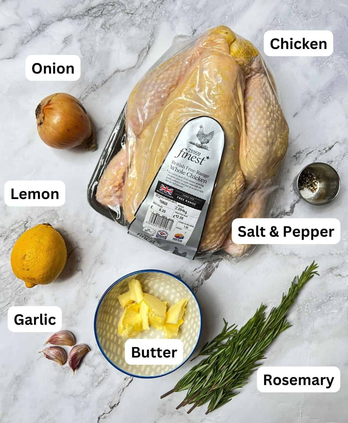 Ingredients laid out for roast chicken with garlic, lemon and rosemary.