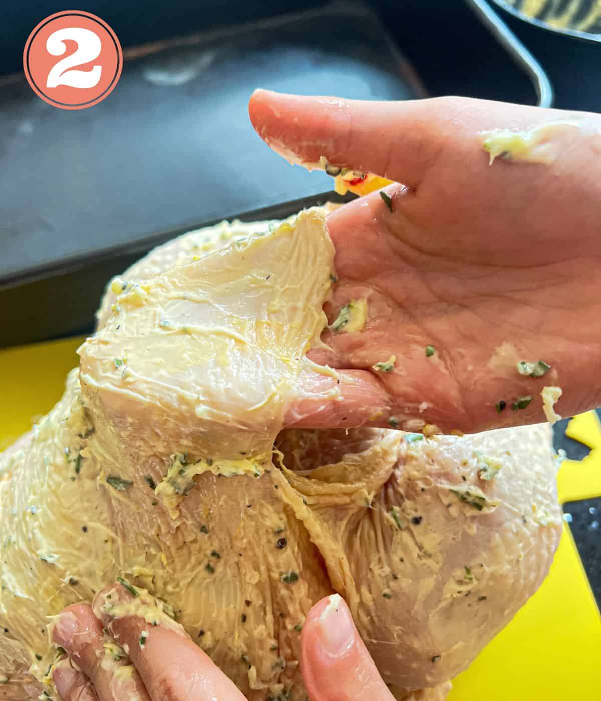 Garlic butter being put under a chicken skin.