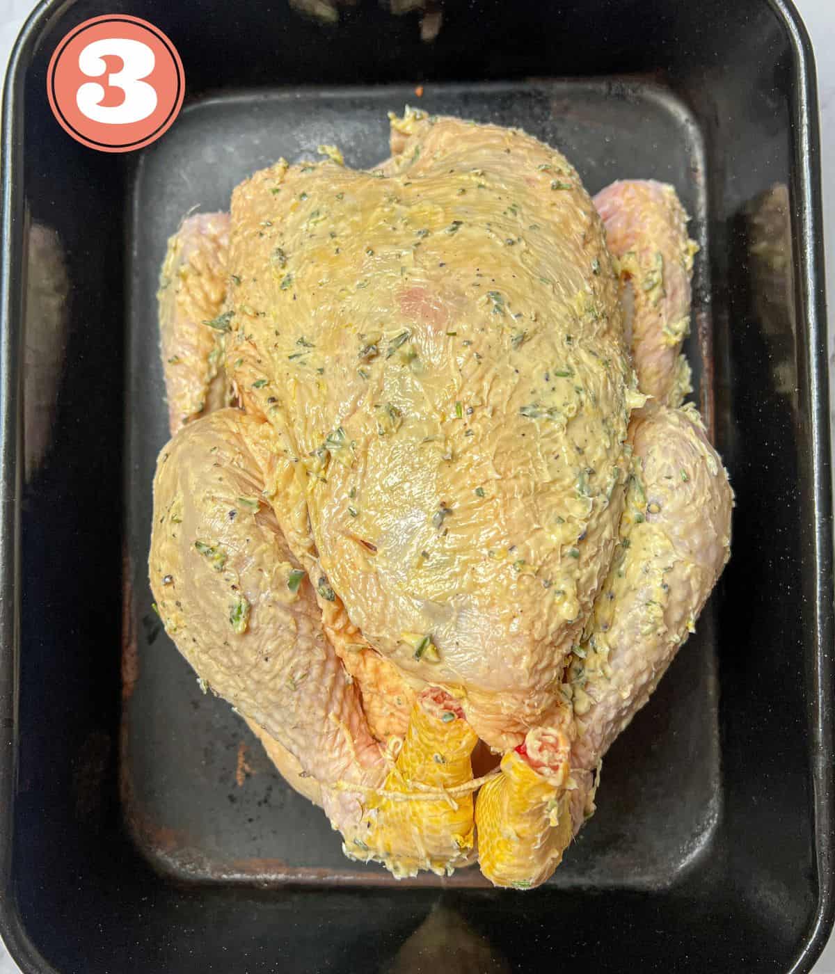 a raw chicken in a roasting tin basted with garlic butter.