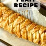 sausage plait on a baking sheet with a spatula under it.