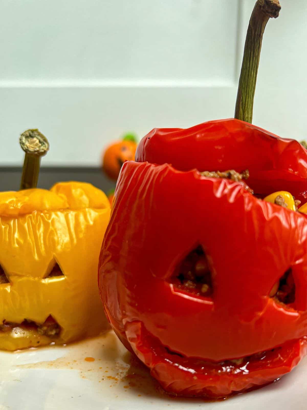 Red and yellow stuffed peppers with faces carved into them.