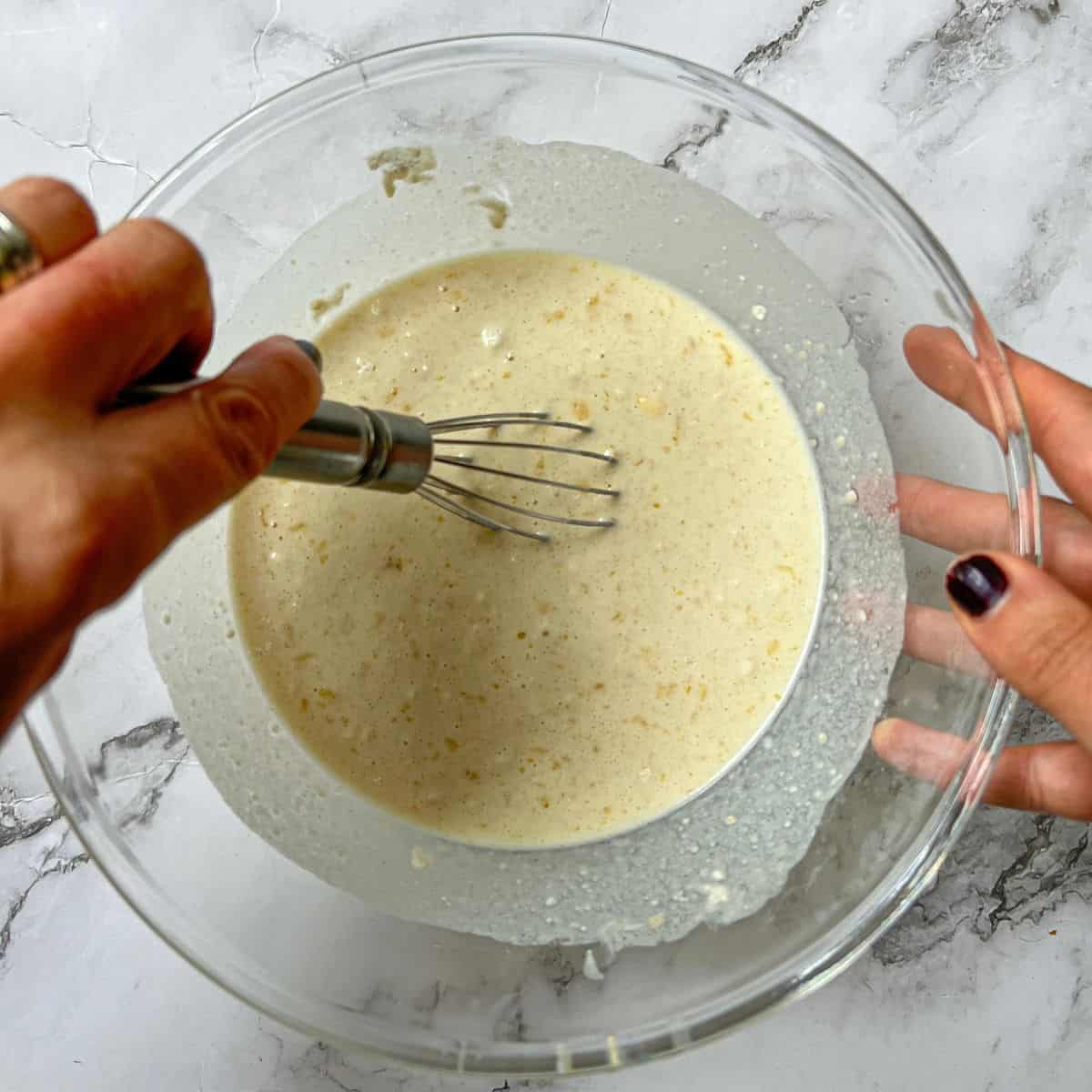 Pancake ingredients being mixed with a hand whisk in a bowl.