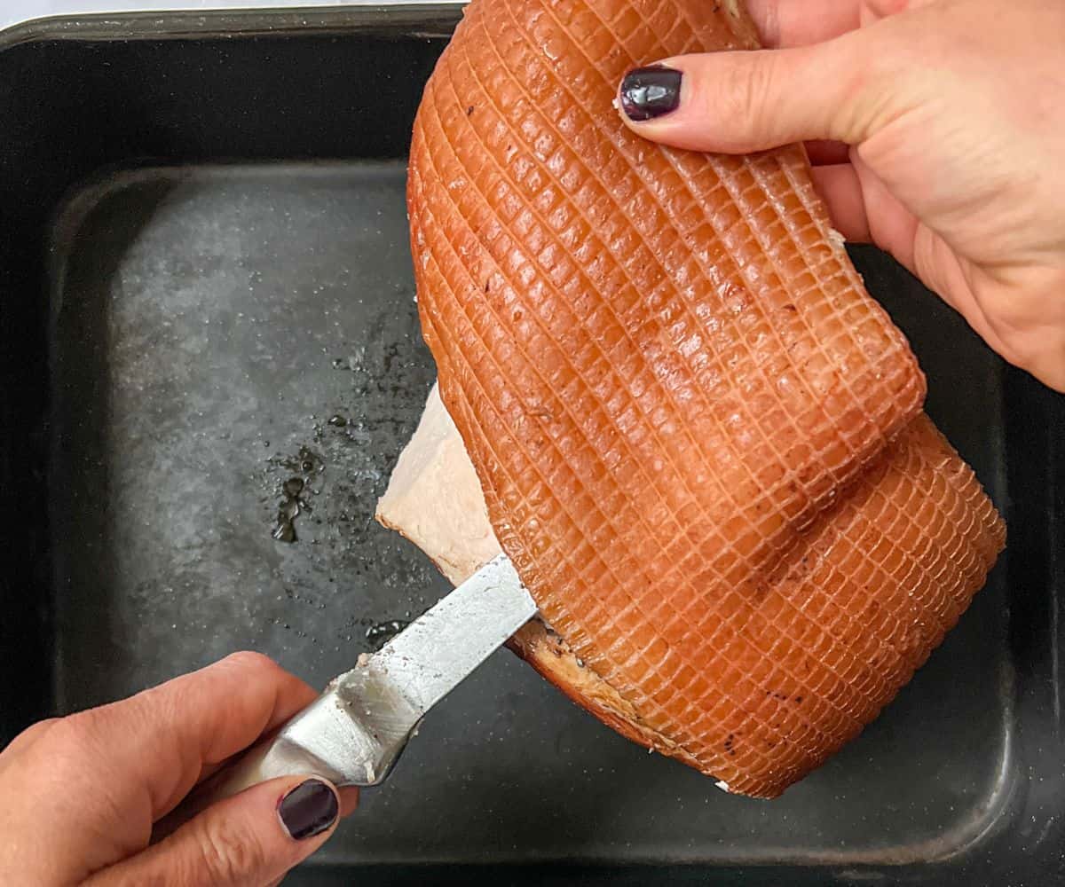 The fat being taken off a cooked gammon joint with a knife.