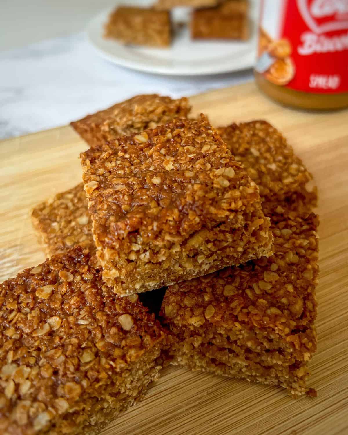 Flapjack squares in a pile on a wooden chopping board.