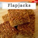 flapjacks stacked in a pile on a wooden chopping board.