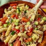 a bowl of tuna pasta salad with a wooden spoon in it.