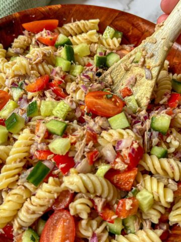 a bowl of tuna pasta salad with a wooden spoon in it.