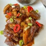 Cooked pork belly in a sauce garnished with red chilli and spring onion.