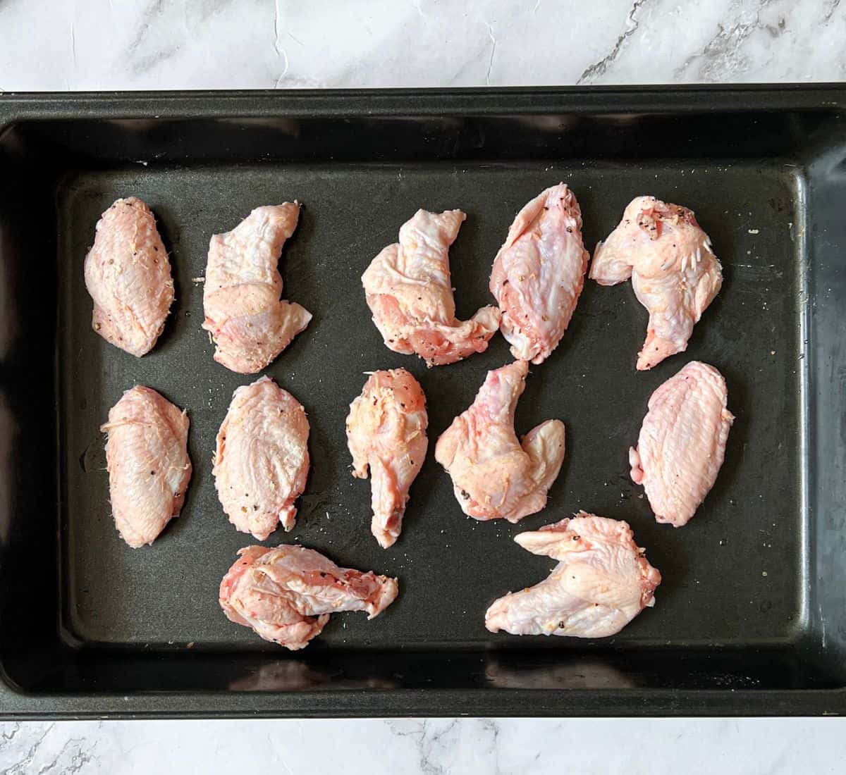 Raw chicken wings on a baking tray.