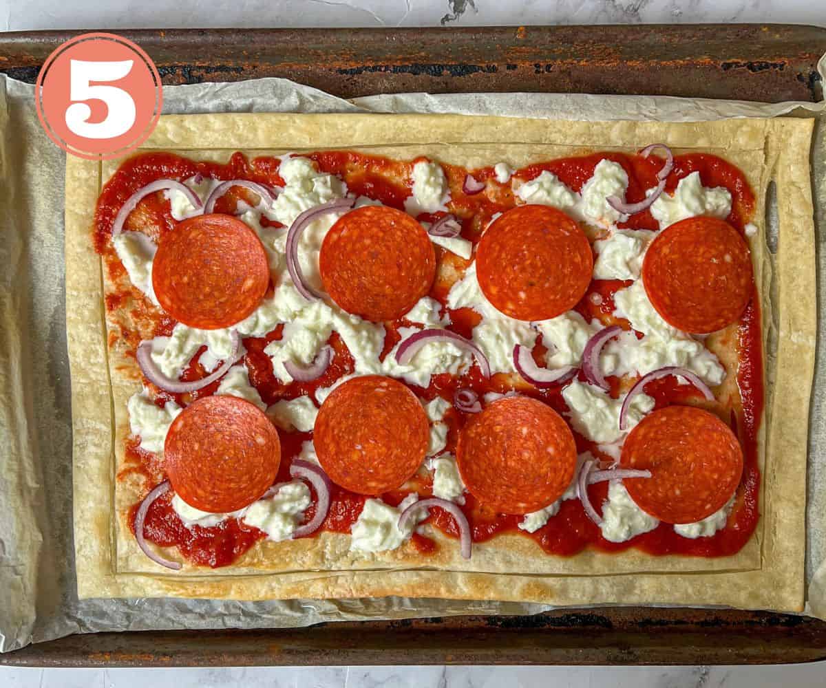 Uncooked rectangle pepperoni pizza on a baking tray.