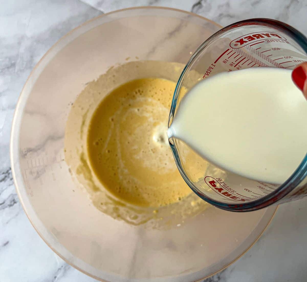 Milk being poured into batter in a mixing bowl.