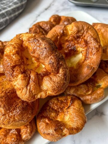 A plate piled high with yorkshire puddings.