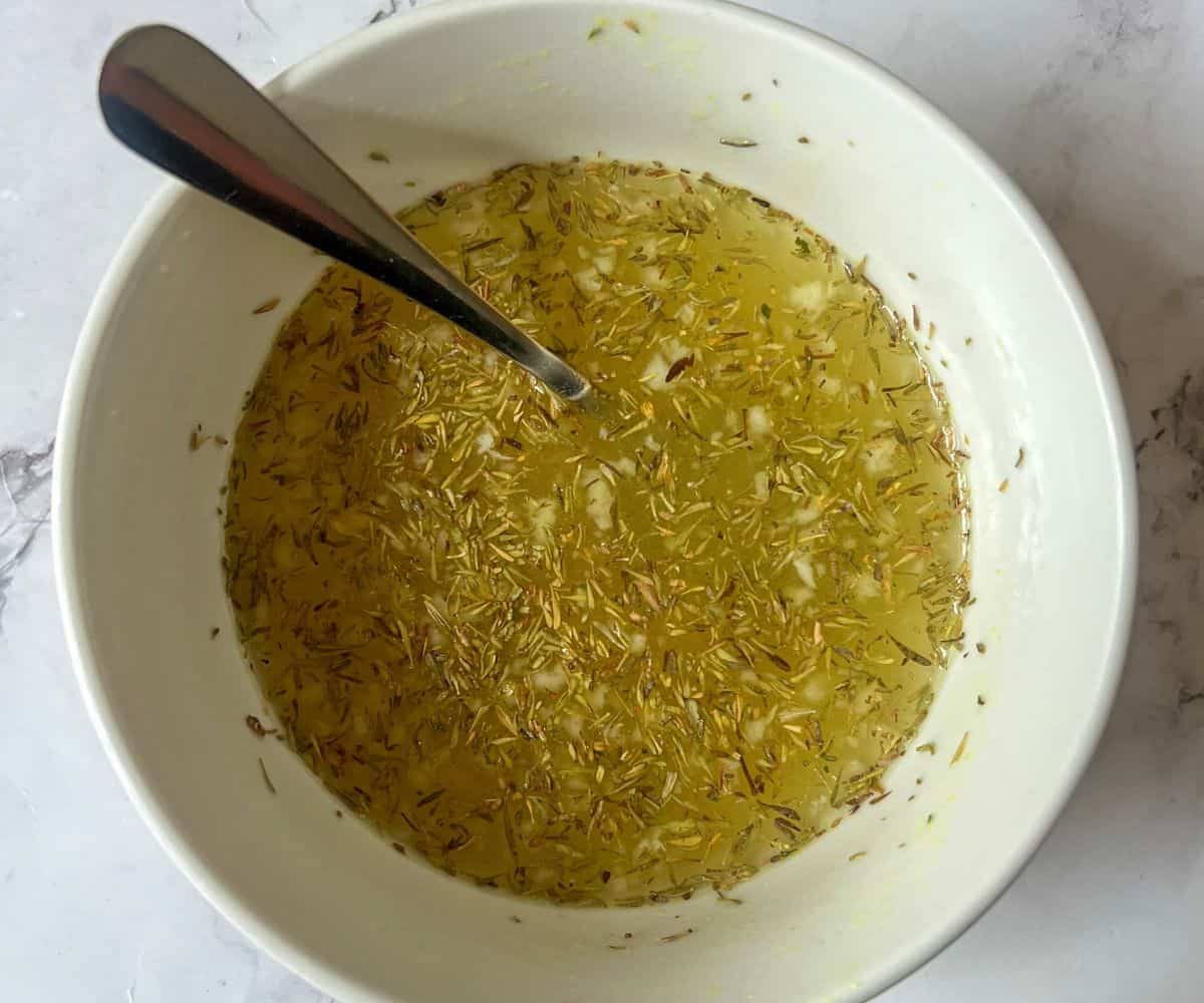 A bowl containing chicken stock and dried thyme.