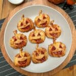 A plate containing 8 puff pastry pumpkin shaped jam hand tarts.