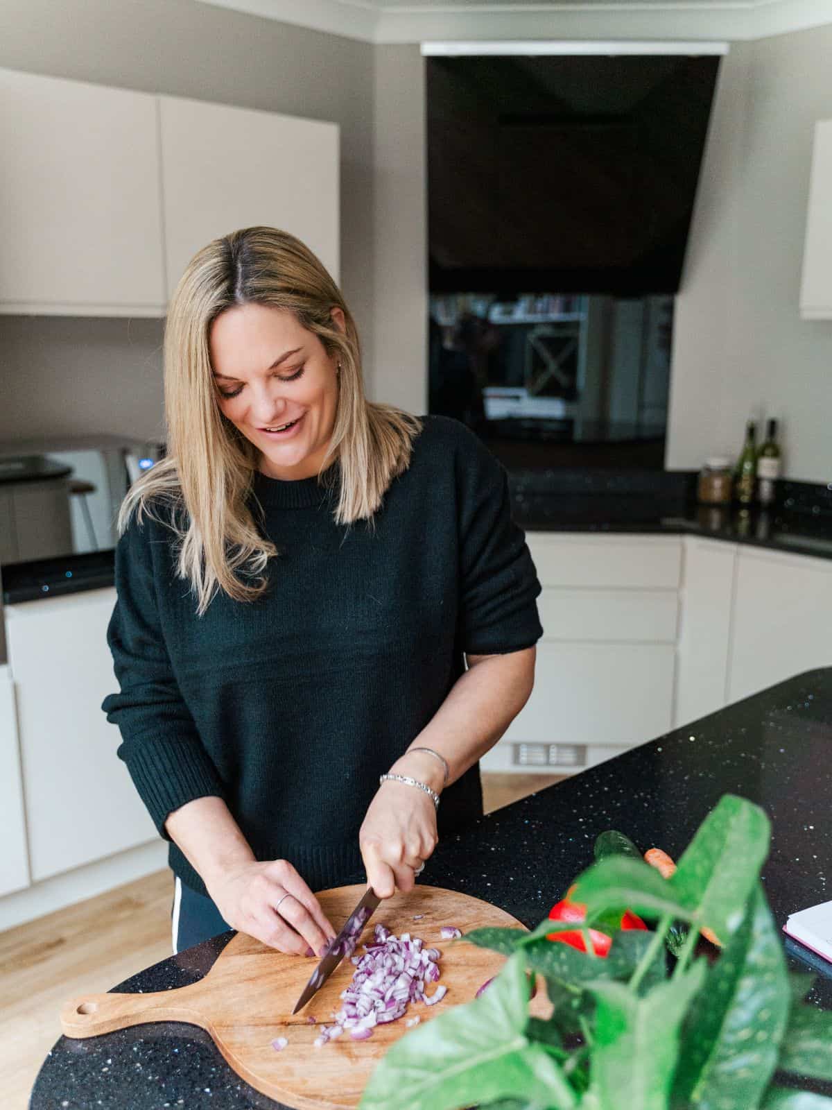 Lady cutting food on a chopping board.