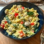 A bowl of orzo with spinach sausage and red pepper.