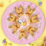 Rice krispie bunny treats on a pink plate garnished with mini eggs.