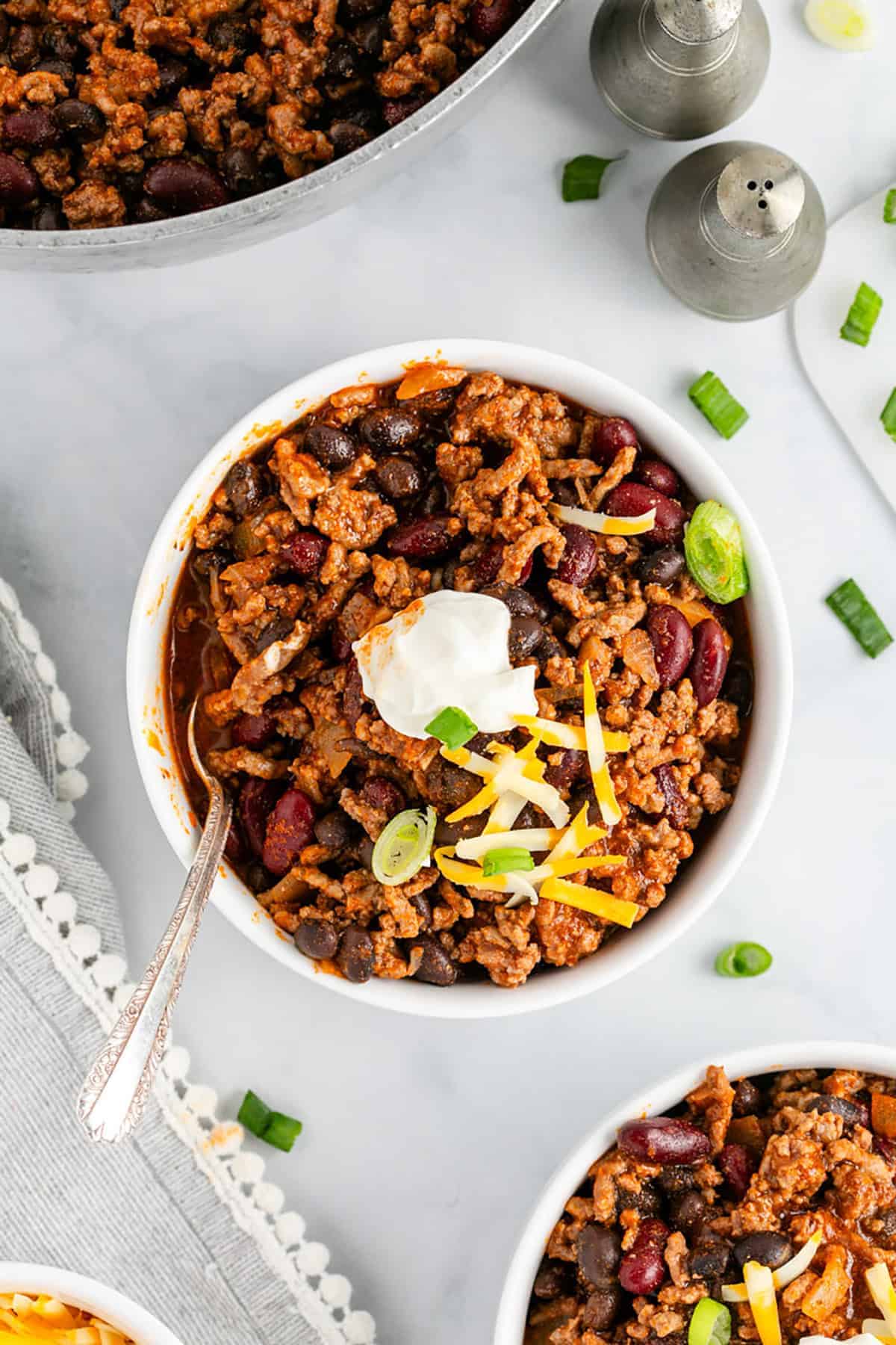 Chilli in bowl topped with sour cream and grated cheese.