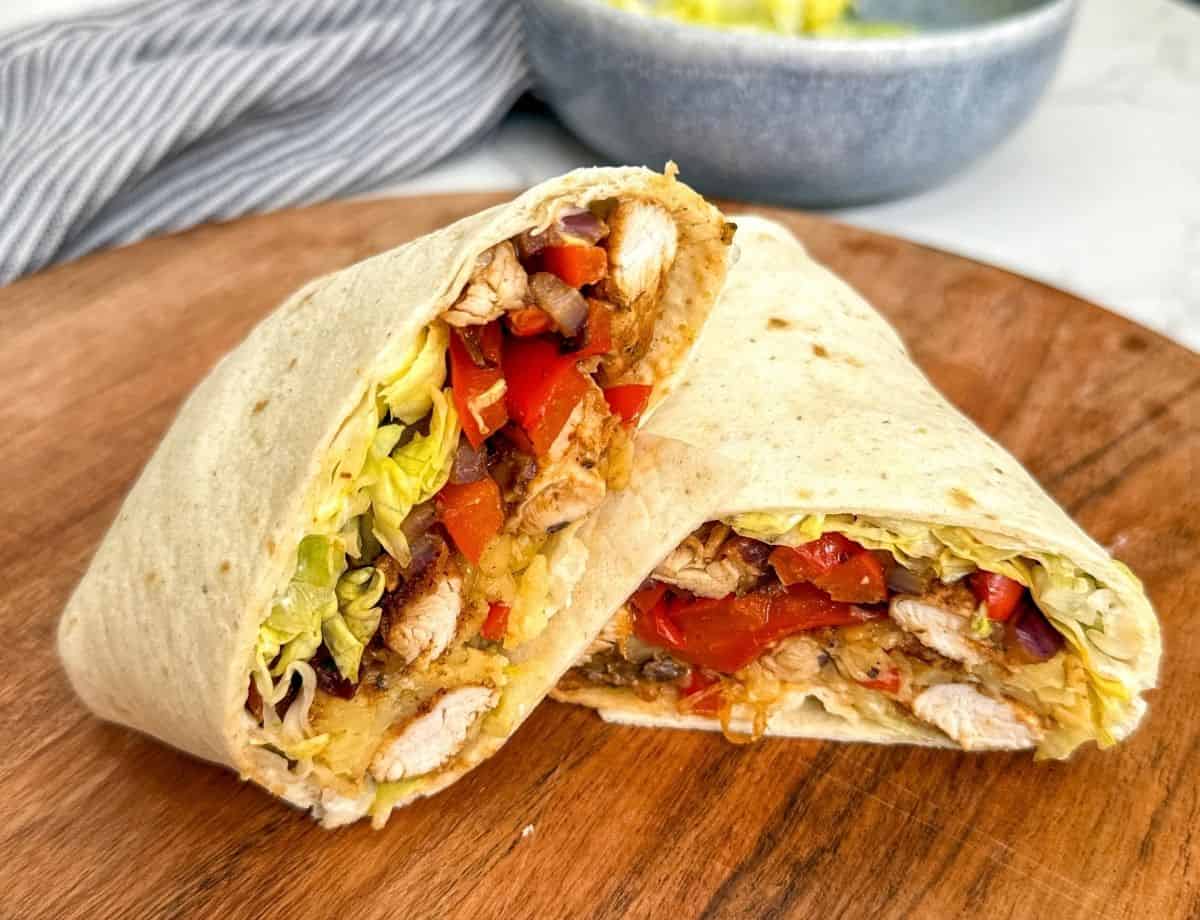 Chicken fajita wrap on a wooden chopping board.