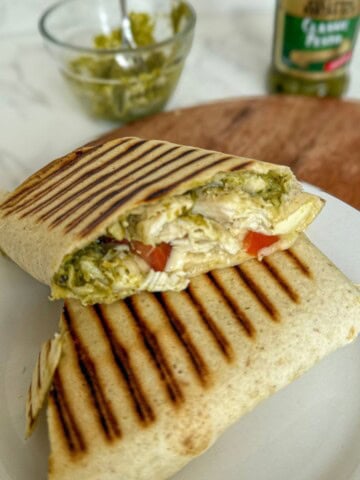 Chicken, tomato, pesto and mozzarella wrap on a white plate.