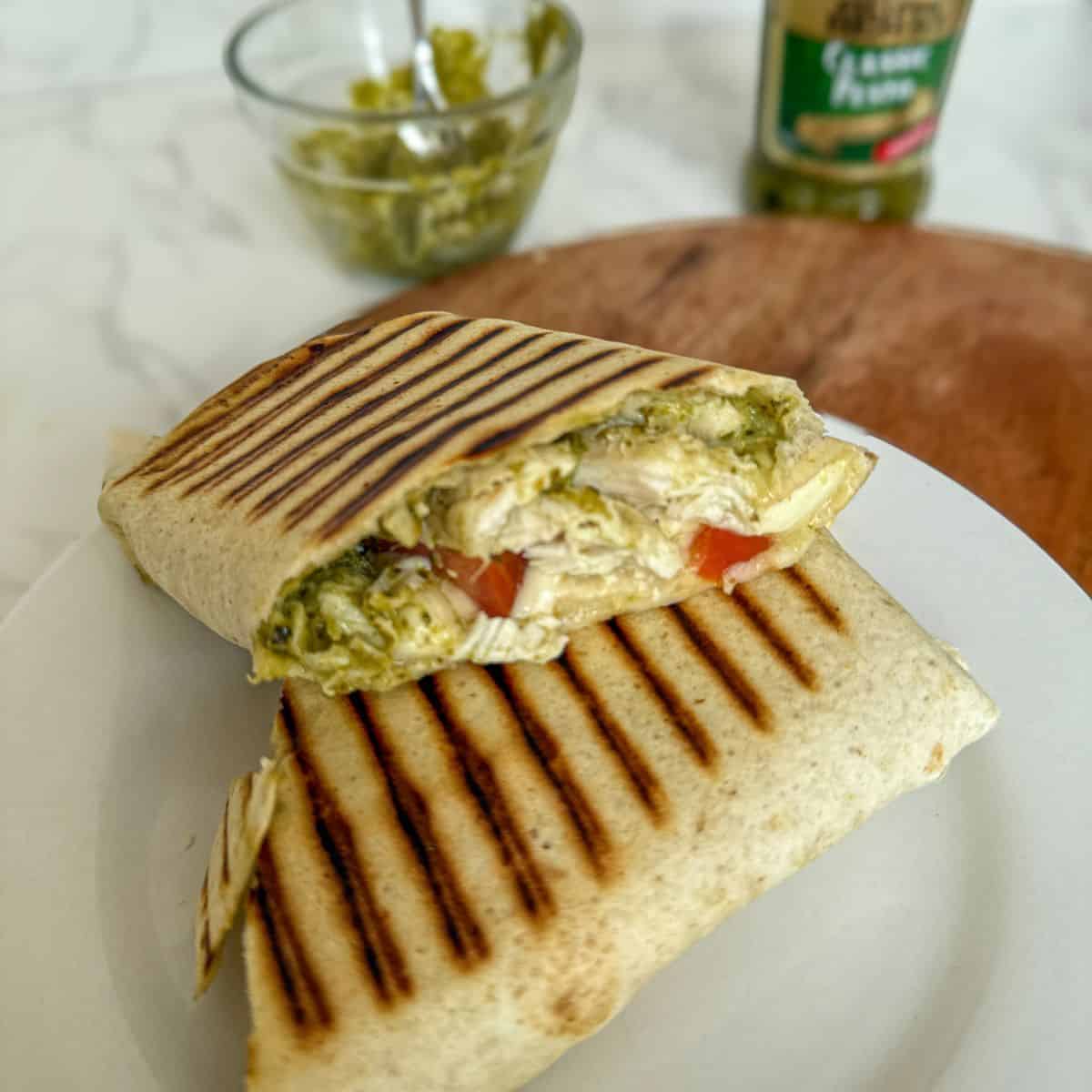 Chicken, tomato, pesto and mozzarella wrap on a white plate.