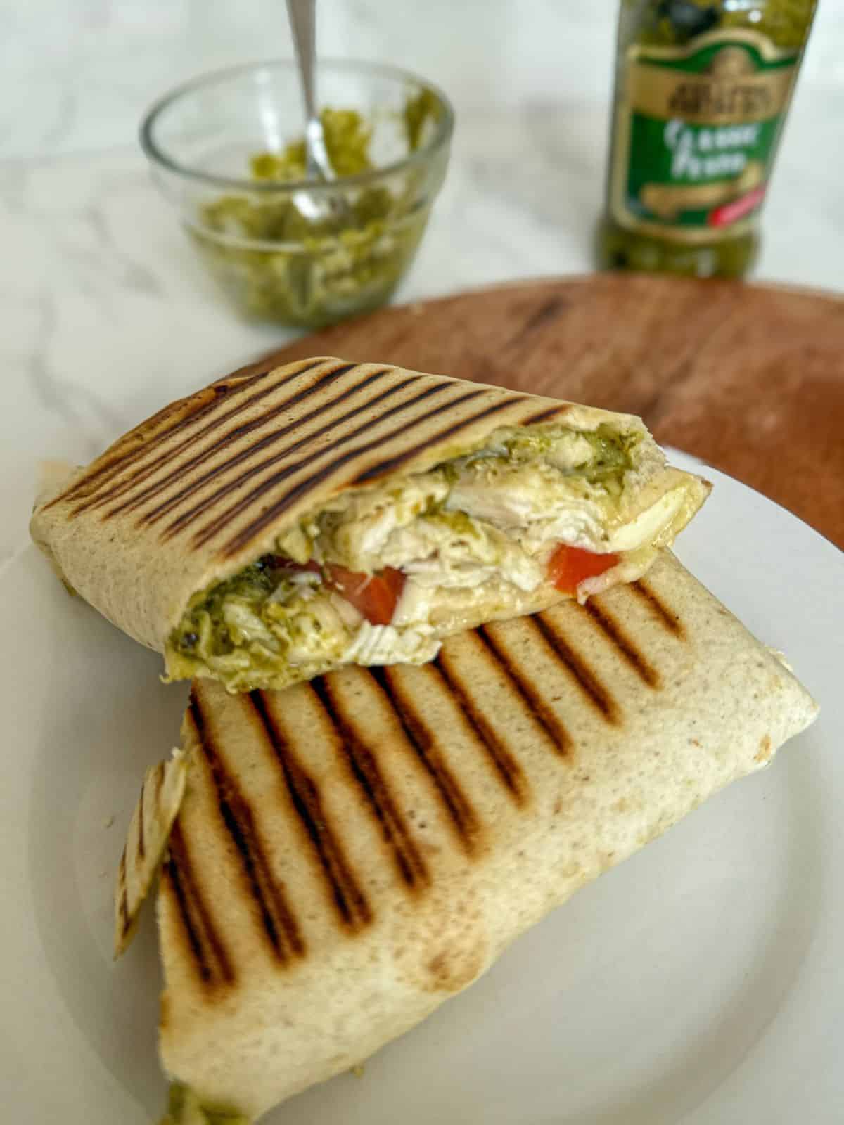 Chicken, tomato, pesto and mozzarella wrap on a white plate.