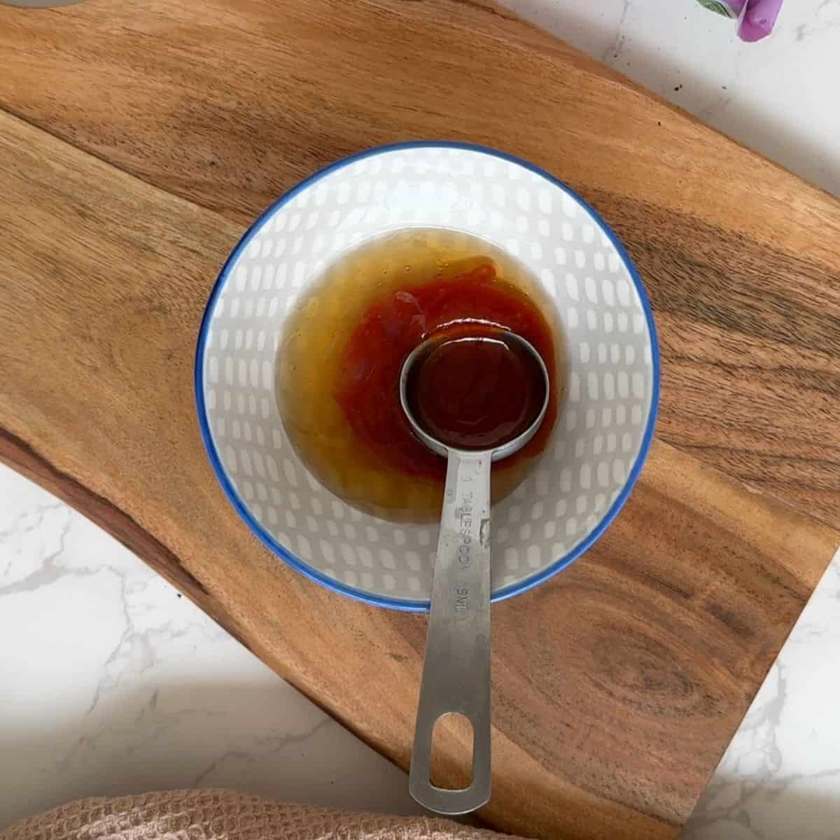Hot honey dressing in a bowl with a spoon in the bowl.
