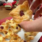 Someone holding a brie and cranberry pastry bite.