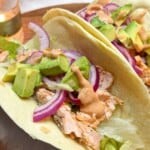 Taco filled with salmon, red onion and avocado with chipotle sauce.