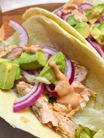 Taco filled with salmon, red onion and avocado with chipotle sauce.