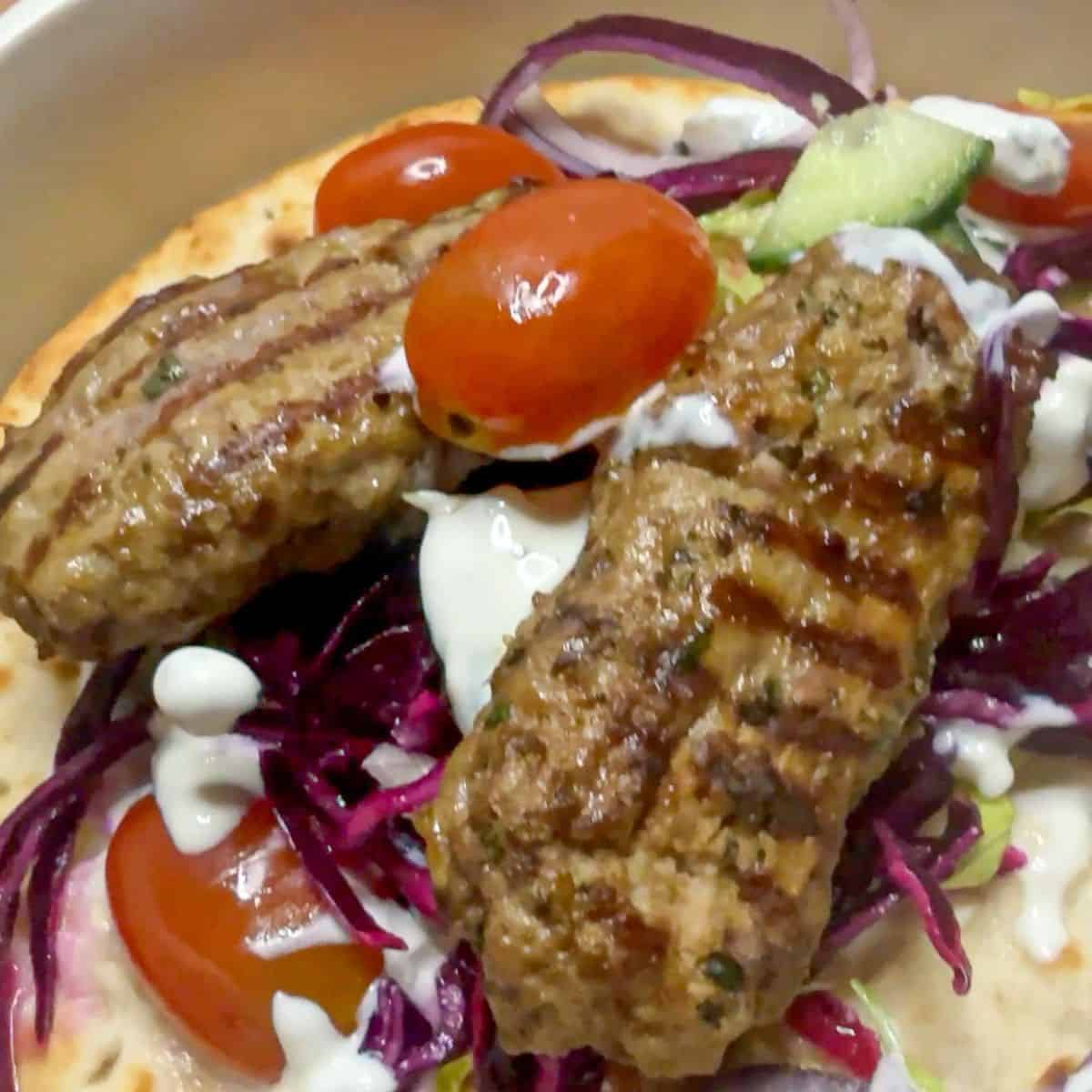 Lamb kofta kebab with tomatoes and red cabbage.