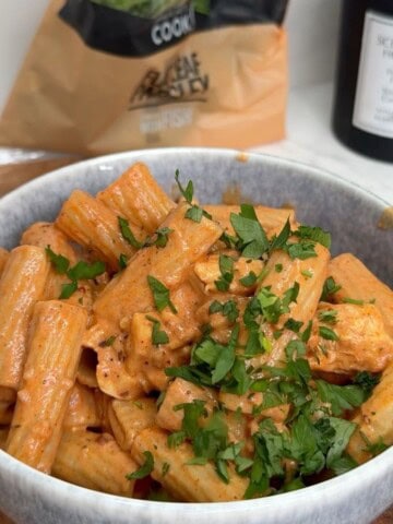 Chicken and halloumi pasta in a bowl garnished with parsley.