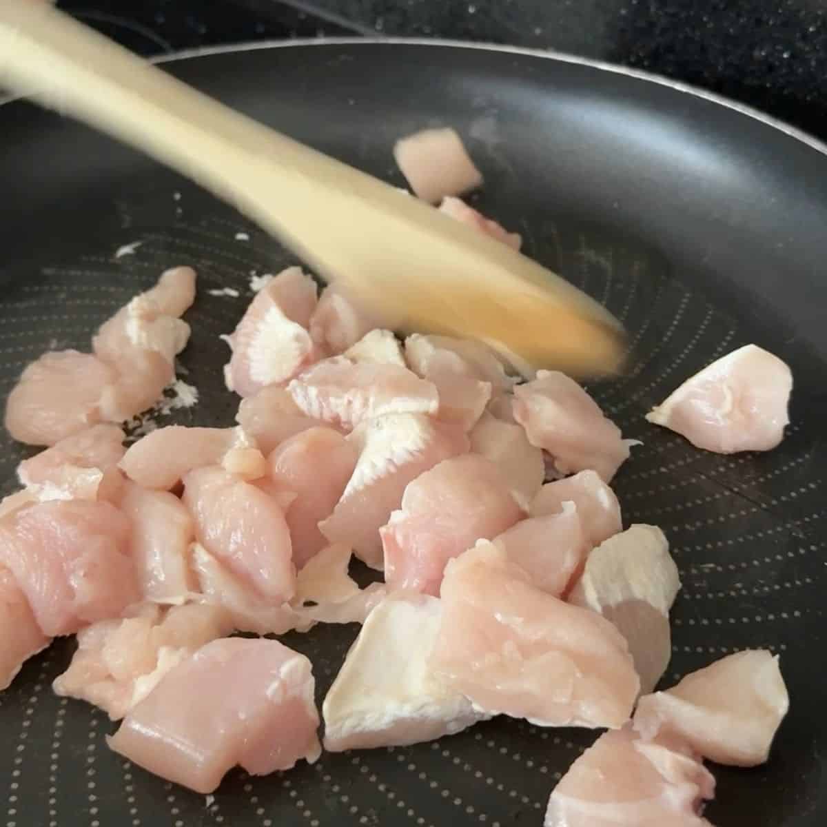 Chicken chunks being cooked in a frying pan.