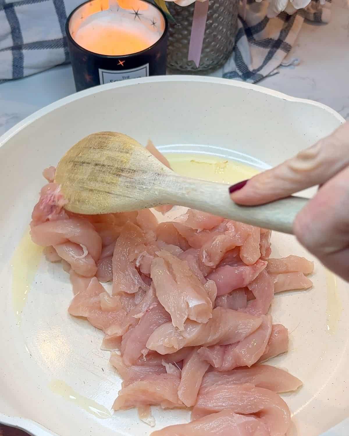 Chicken strips being cooked in a frying pan.
