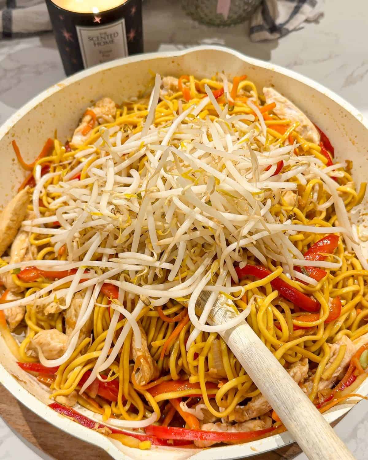 Chicken chow mein being cooked in a frying pan.