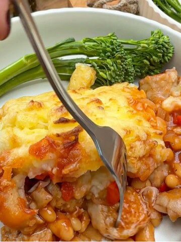 A plate of cowboy pie with a side of tenderstem broccoli.