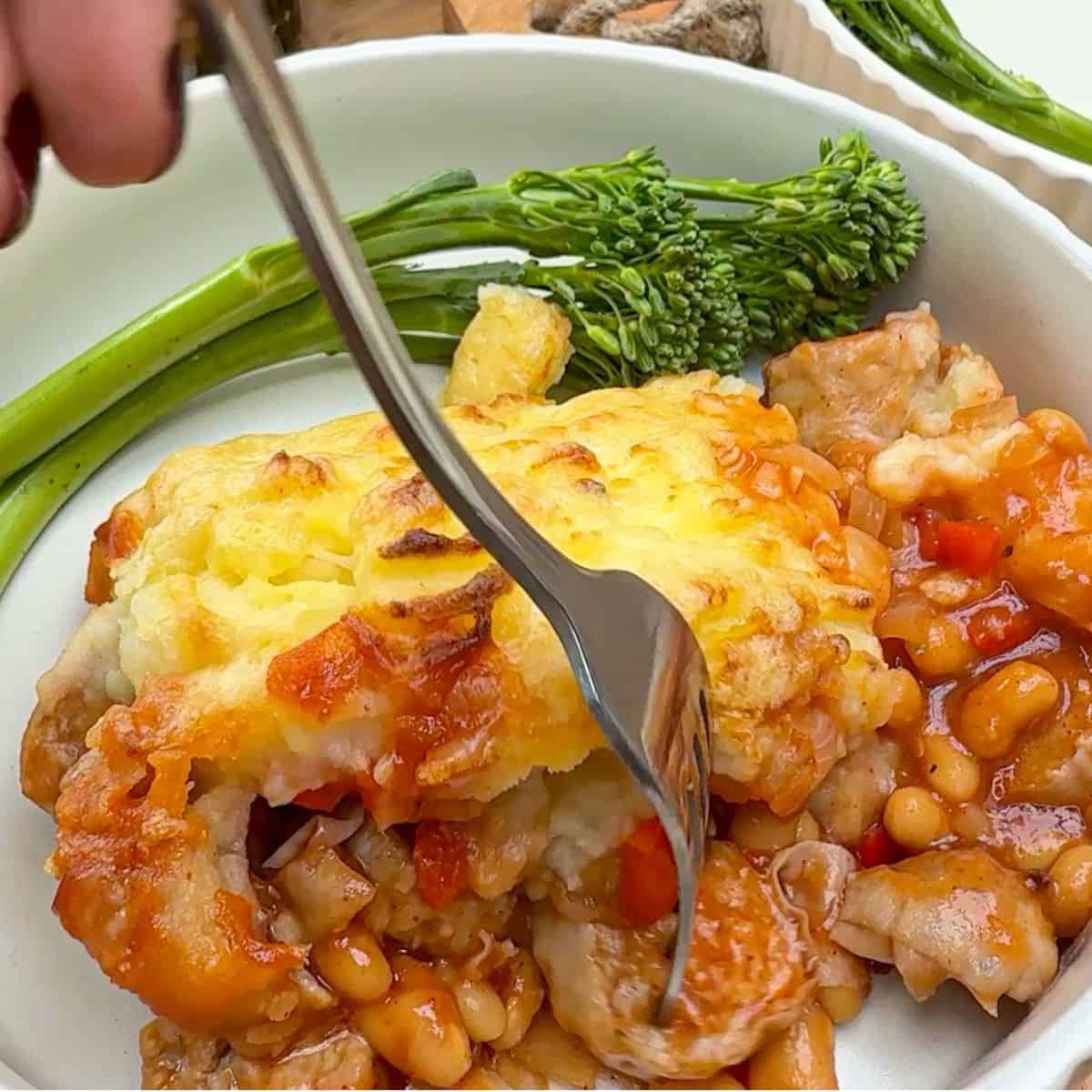 A plate of cowboy pie with a side of tenderstem broccoli.