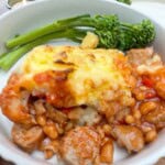 A bowl of cowboy pie with a side of tenderstem broccoli.
