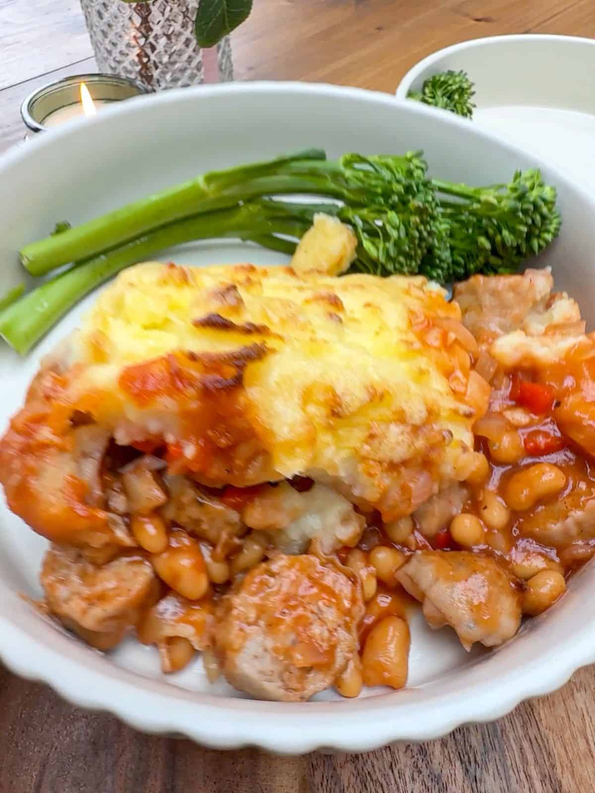 A bowl of cowboy pie with a side of tenderstem broccoli.