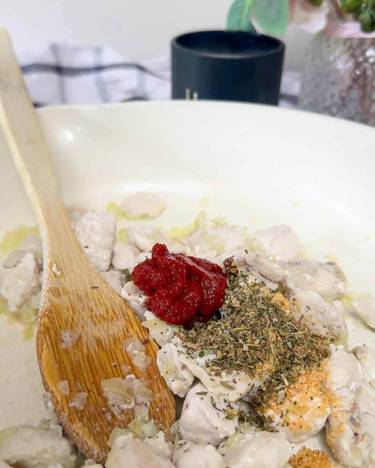Chopped chicken and onions in a pan with tomato puree and herbs.