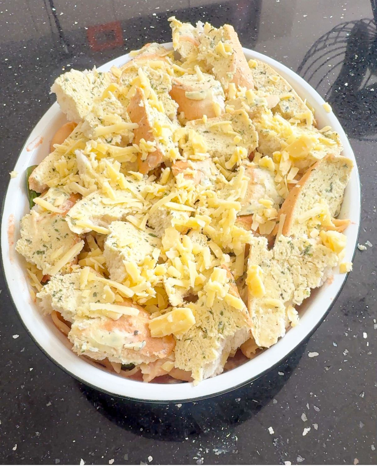 Torn garlic bread in a white bowl topped with grated cheese.