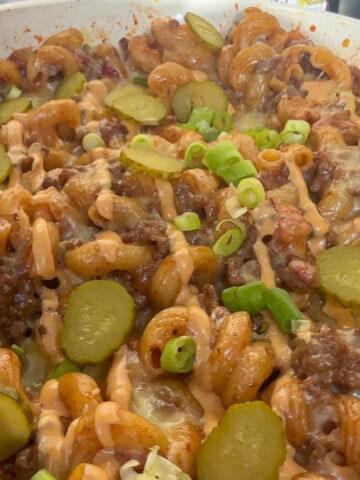 Cheeseburger pasta topped with gherkins and burger sauce.