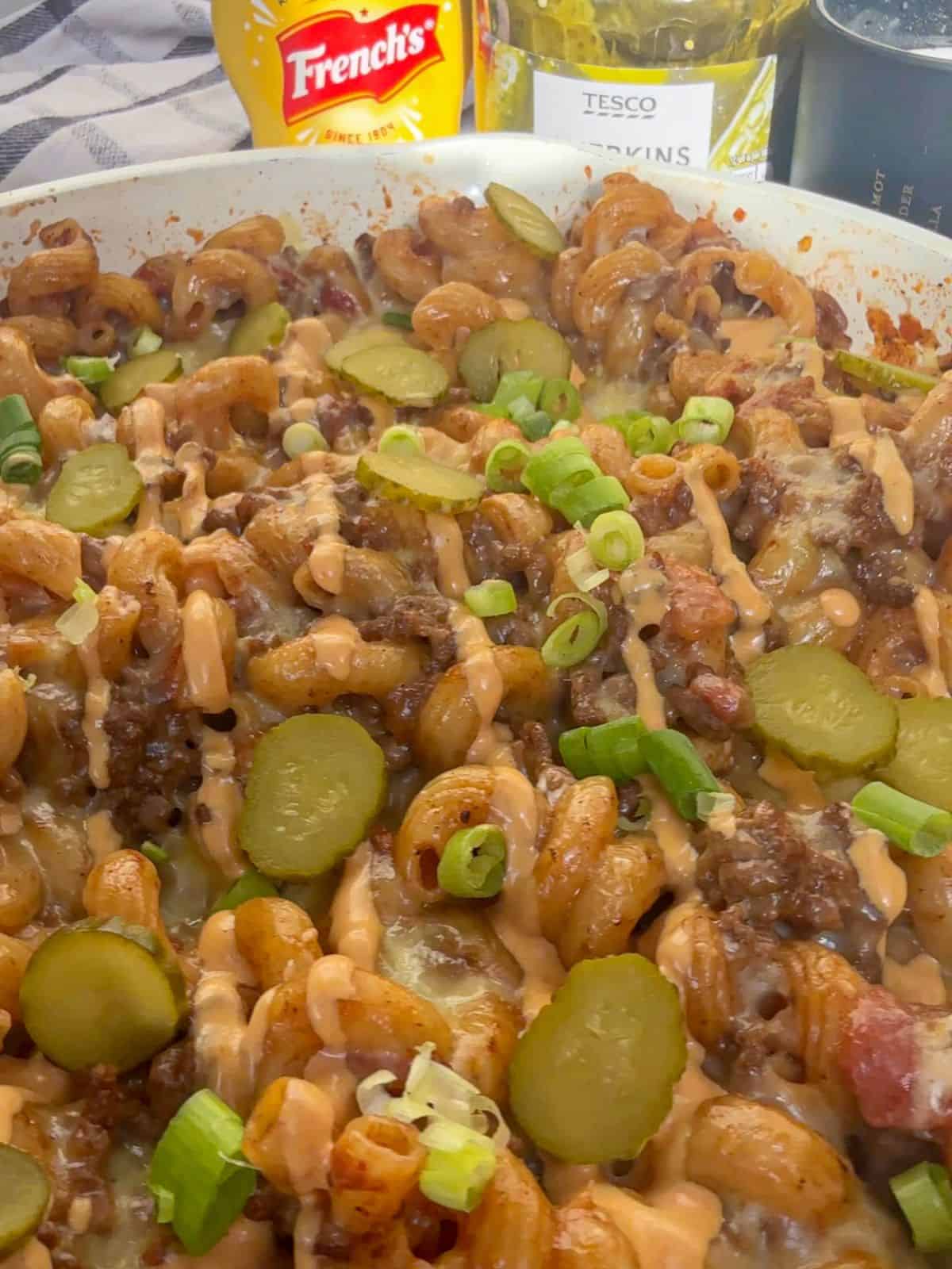 Cheeseburger pasta topped with gherkins and burger sauce.
