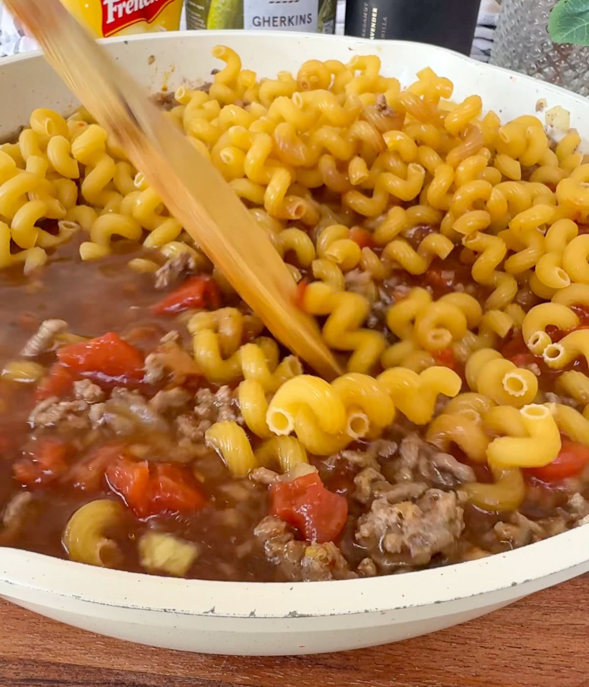 Spiral pasta and mince being stirred in a pan.